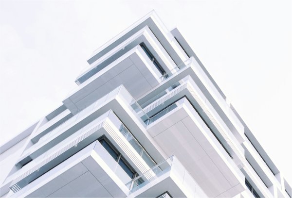 Contemporary white high-rise building photographed from below, illustrating modern real estate assets and digital transformation in property financing at Berlin Hyp.
