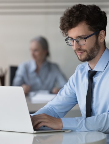 Professional working on a laptop in an office environment, representing digital workflows, automation, and improved user experience developed for Berlin Hyp.
