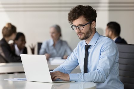 Bank employee working on a laptop in an office setting, representing a transparent and automated credit workflow at Berlin Hyp.