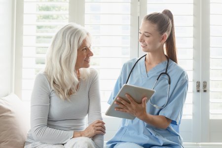Healthcare professional discussing care with a patient using a tablet, representing human-centered digital health solutions at Future Health Lab.