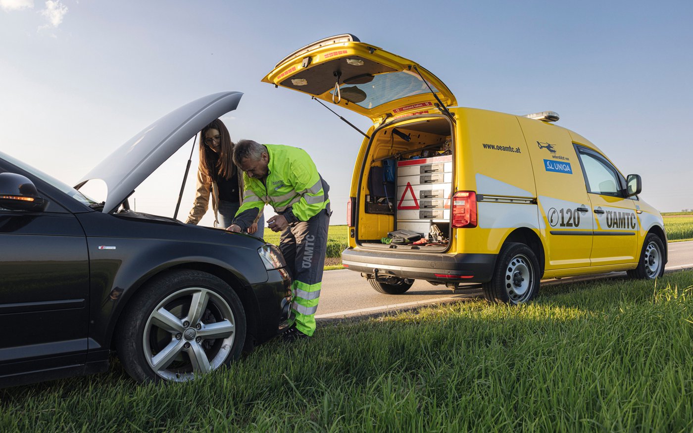 Roadside assistance technician repairing a broken-down car next to a service vehicle, showcasing AI-powered waiting time prediction and efficient mobility service operations.