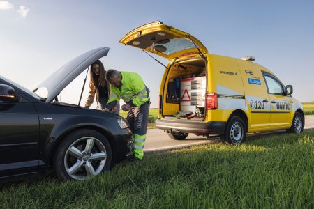 Roadside assistance technician repairing a broken-down car next to a service vehicle, showcasing AI-powered waiting time prediction and efficient mobility service operations.