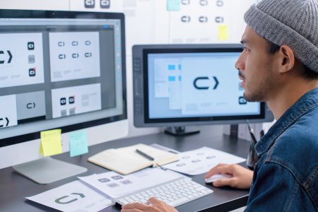 Designer working on a digital design system across multiple screens, ensuring consistent UI components and scalable product design.