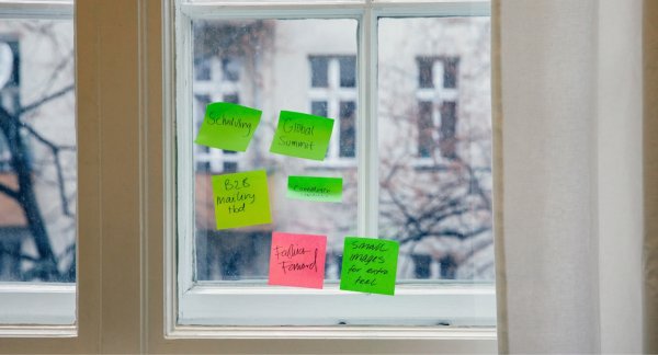 Colorful sticky notes arranged on a window during a collaborative design thinking session focused on system and workflow innovation
