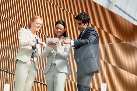 Three banking professionals reviewing a tablet together, representing Raiffeisen’s digital onboarding redesigned through design thinking.