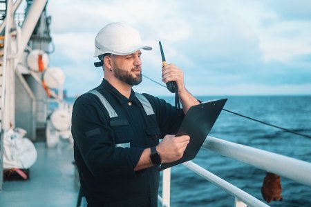 Maritime inspector on a ship using a clipboard and radio, representing automated CO₂ monitoring and auditing workflows by Swiss Climate.