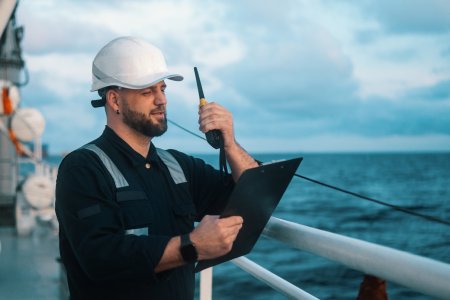 Auditor im Schiffsverkehr prüft CO₂-Emissionen mit Funkgerät und Klemmbrett – digitale Auditierungsprozesse von Swiss Climate umgesetzt mit Sclable Workflow Intelligence.