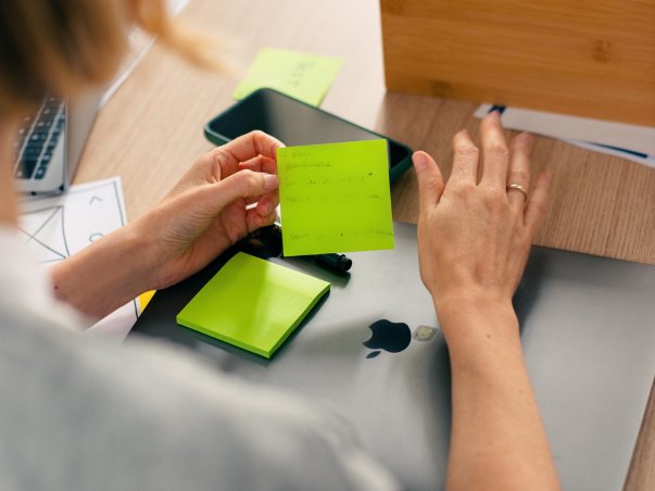 Hand hält Post-it-Note über Laptop