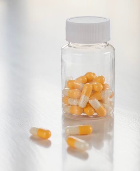 Clear screw-top bottle containing yellow pills, indicating a case study about the healthcare industry