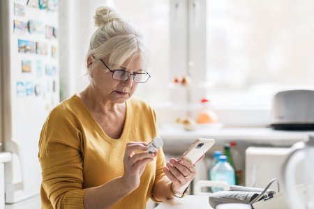 Older woman using a smartphone to check medication details in her home, illustrating a digital health experience from the Zur Rose case study.