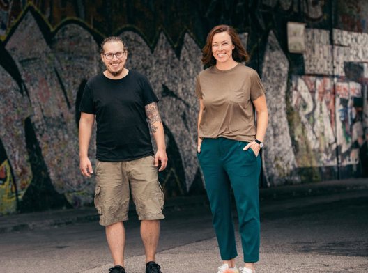 Three sclable team members leaning up against wall covered in street art
