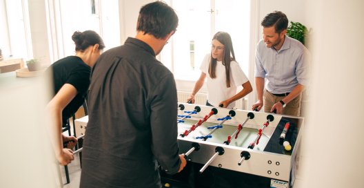 Four sclable team members playing table football together