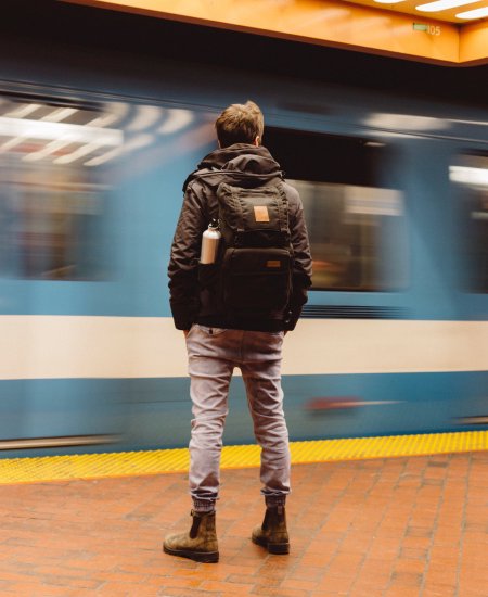 Mann steht auf dem Bahnsteig während ein Zug vorbeifährt